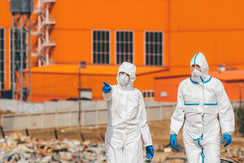 two people in protective suits walking through debris